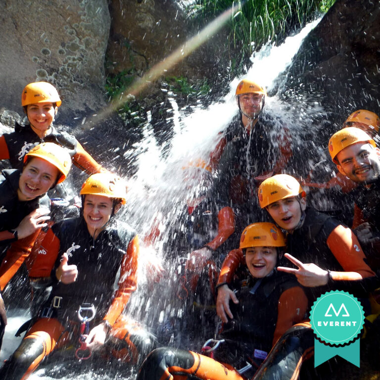 Grupo de amigos sonríe a cámara junto a una pequeña cascada en una ruta de barranquismo en Cáceres