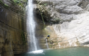 Chico descendiendo por una cuerda hasta el agua en una ruta de vía ferrata en Huesca