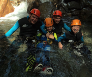 Familia sonríe felizmente en un río en una ruta de barraquismo en Huesca