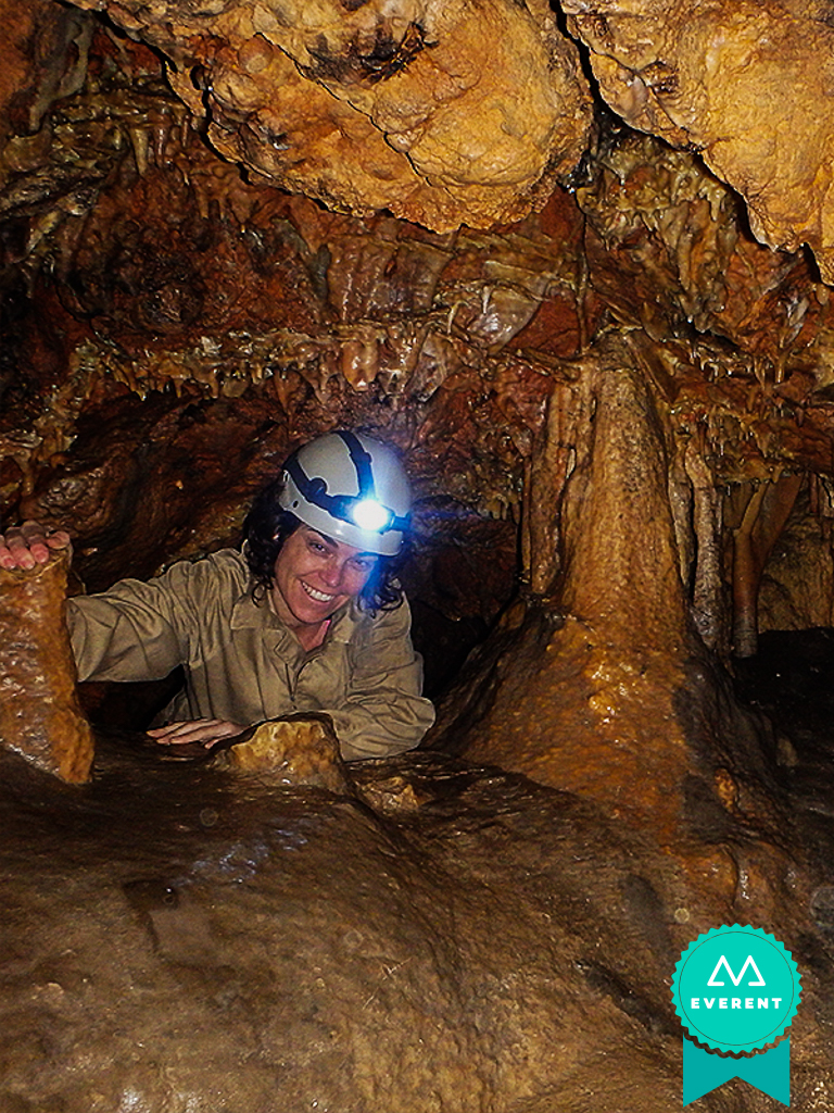 Chica sonríe mientras cruza una cueva en una ruta de espeleología en Valencia