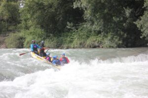 Grupo de personas descendiendo por aguas bravas en una ruta de rafting en Huesca