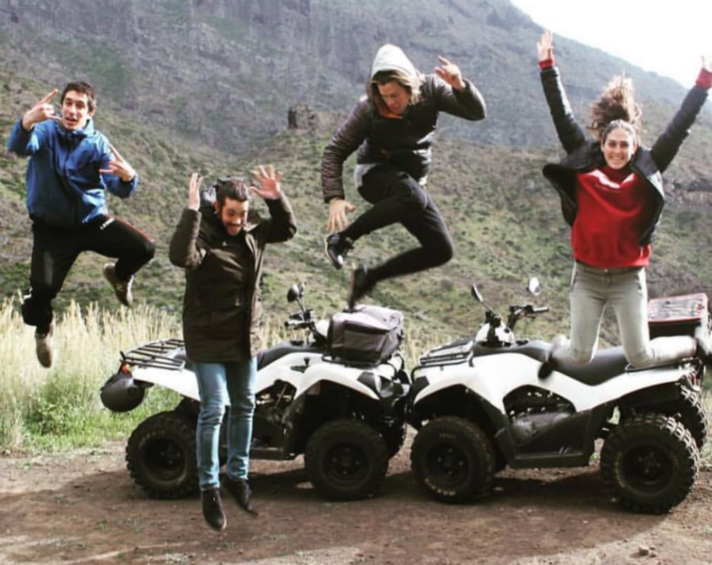Amigos saltan sonrientes jen una excursión en quad por la zona de Masca, Tenerife.